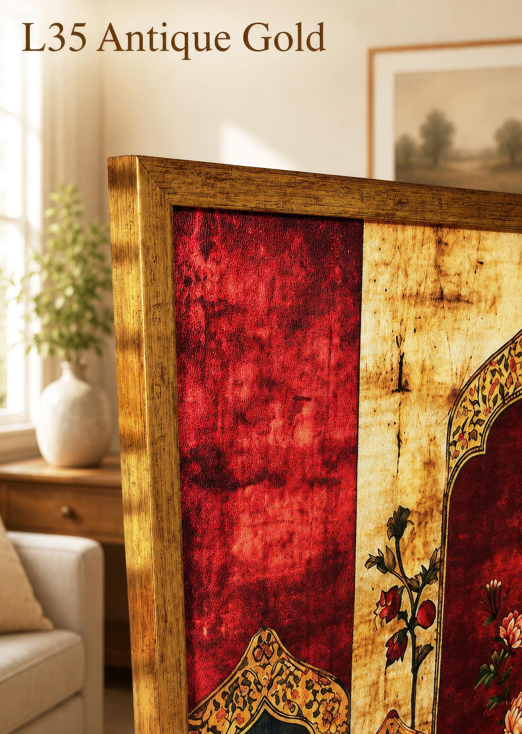 a close-up view of a gold-colored antique frame with a red and gold floral design, placed on a wooden surface. In the background, there is a window with a plant and a painting on the wall.