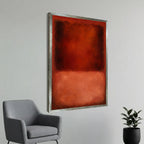 a large, abstract painting with a bold red and orange color scheme, hanging on a white wall next to a gray armchair.